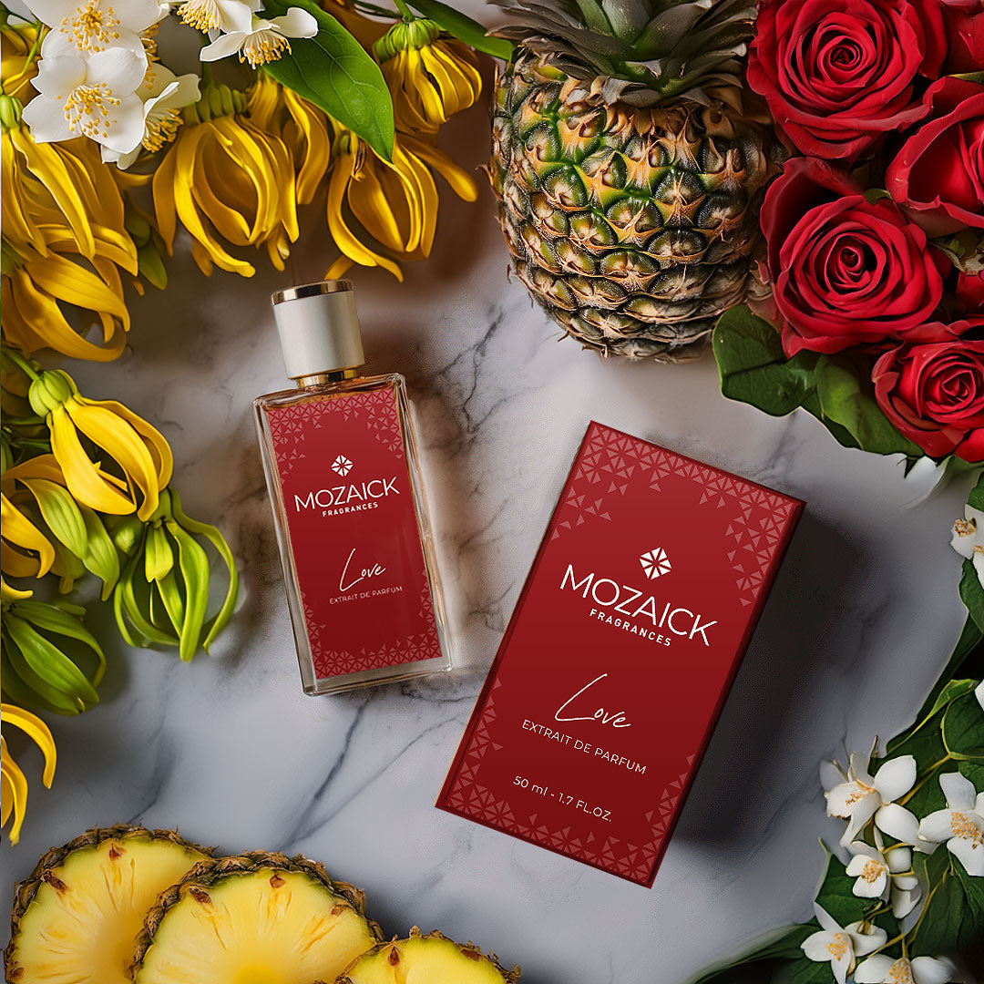 LOVE Extrait de Parfum 50 ml by MOZAICK – bottle and box on marble with red roses, pineapple and yellow flowers